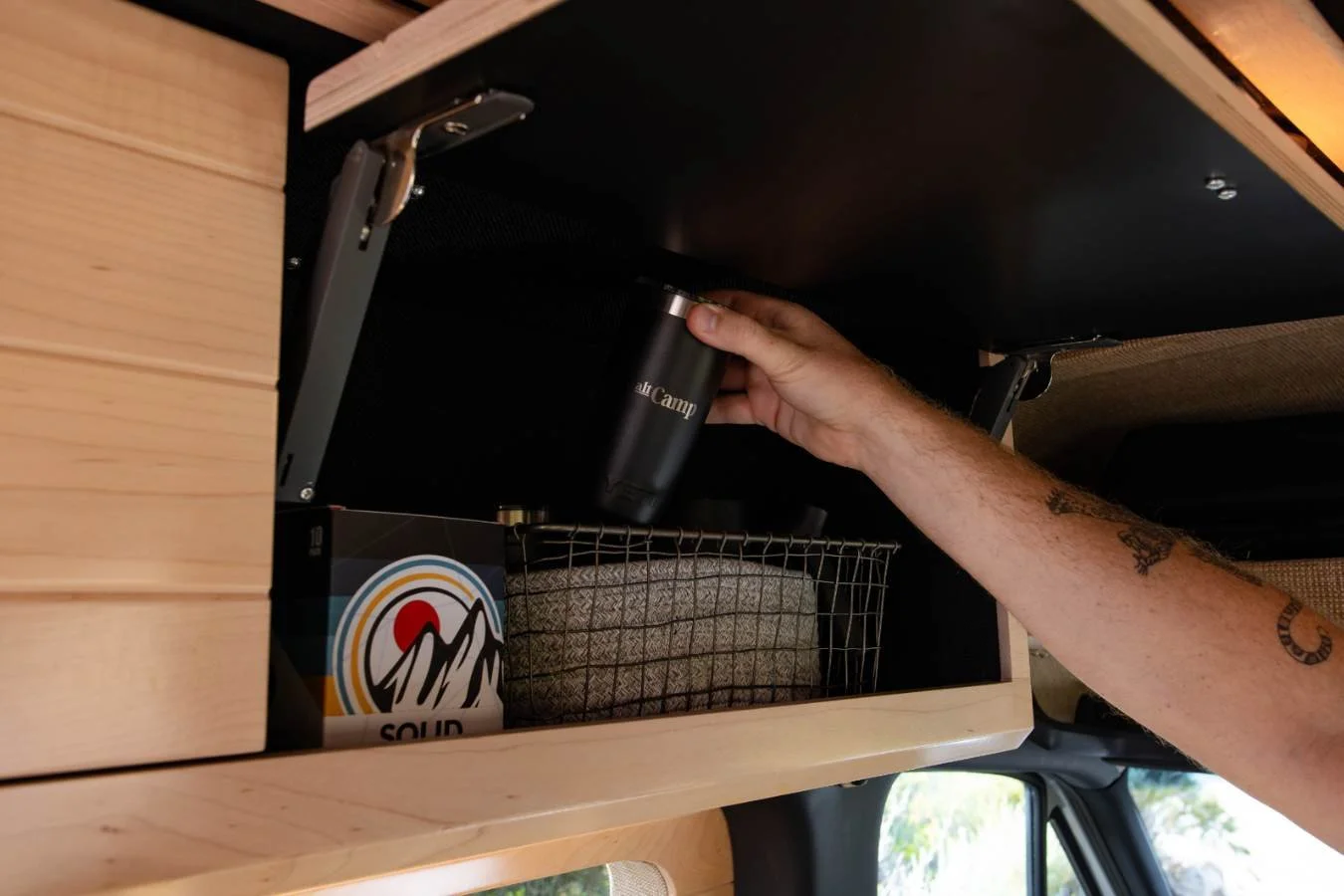 Overhead storage cabinet with coffee station inside premium Sprinter camper van conversion.