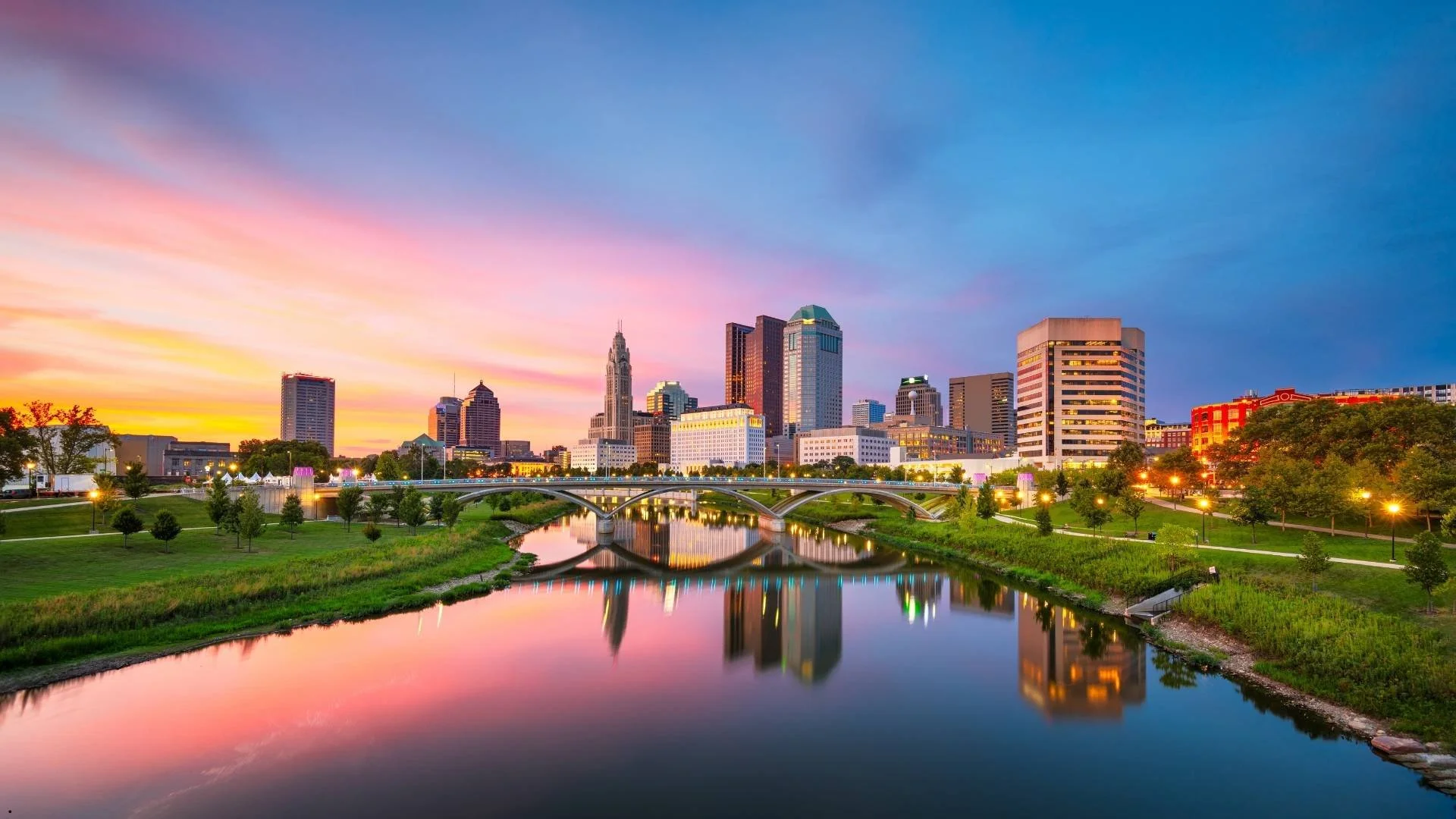 Columbus, Ohio skyline at sunset reflected in the Scioto River, near camper van rental starting points for exploring Ohio.