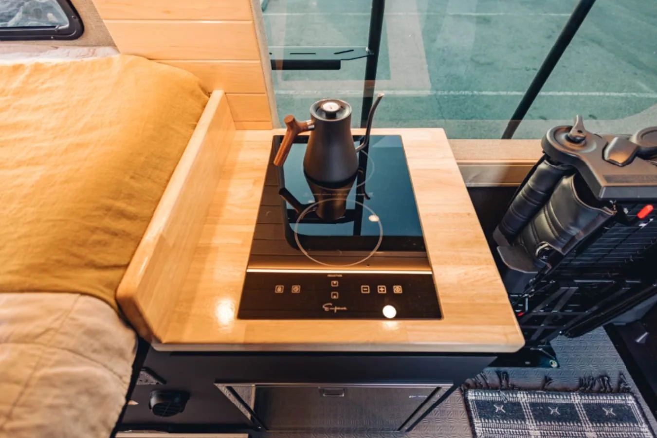 Induction cooktop and kitchenette inside premium camper van interior.