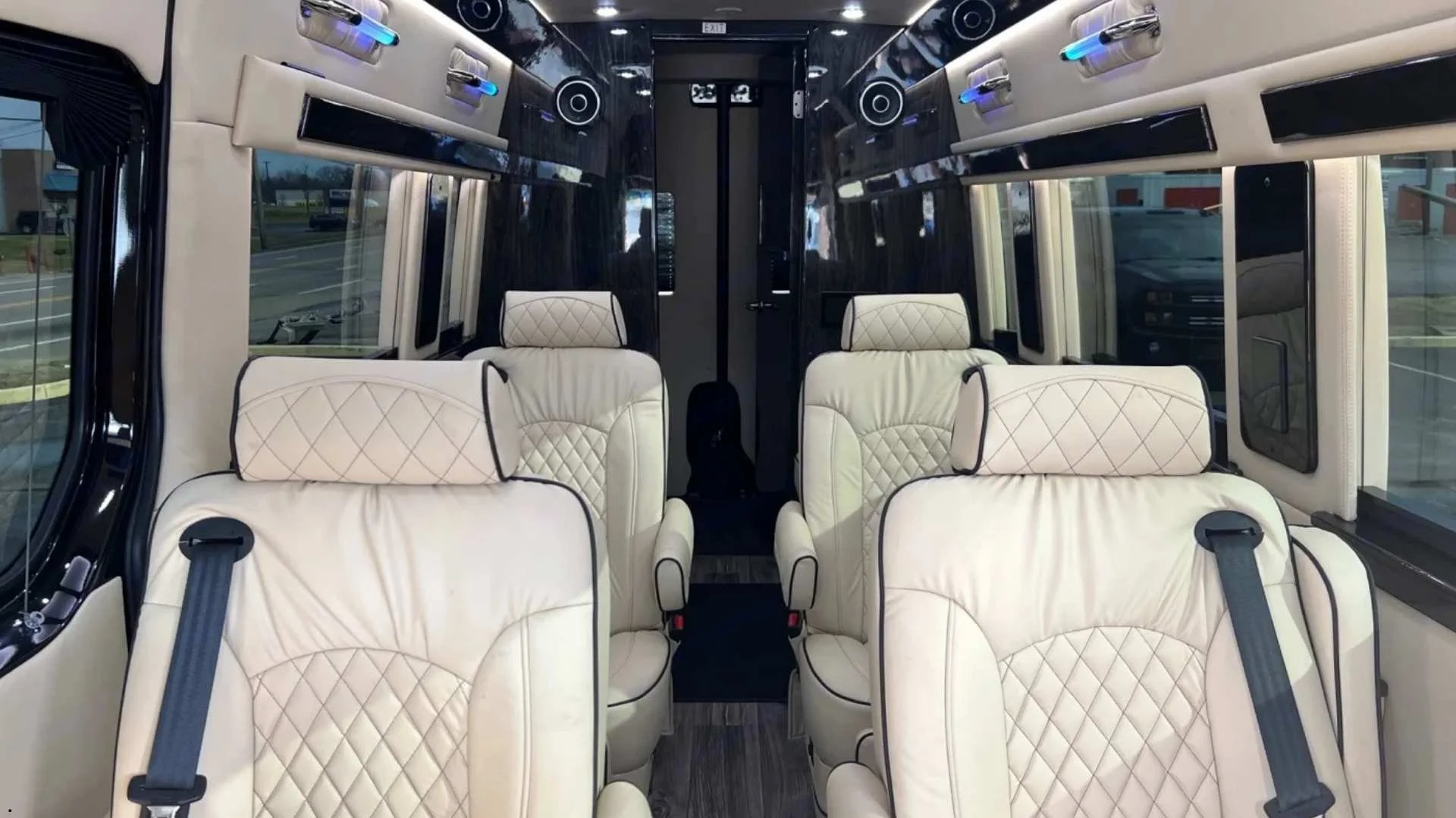 Interior of a luxury passenger van rental featuring plush leather captain’s chairs, LED accent lighting, and a spacious executive-style cabin.