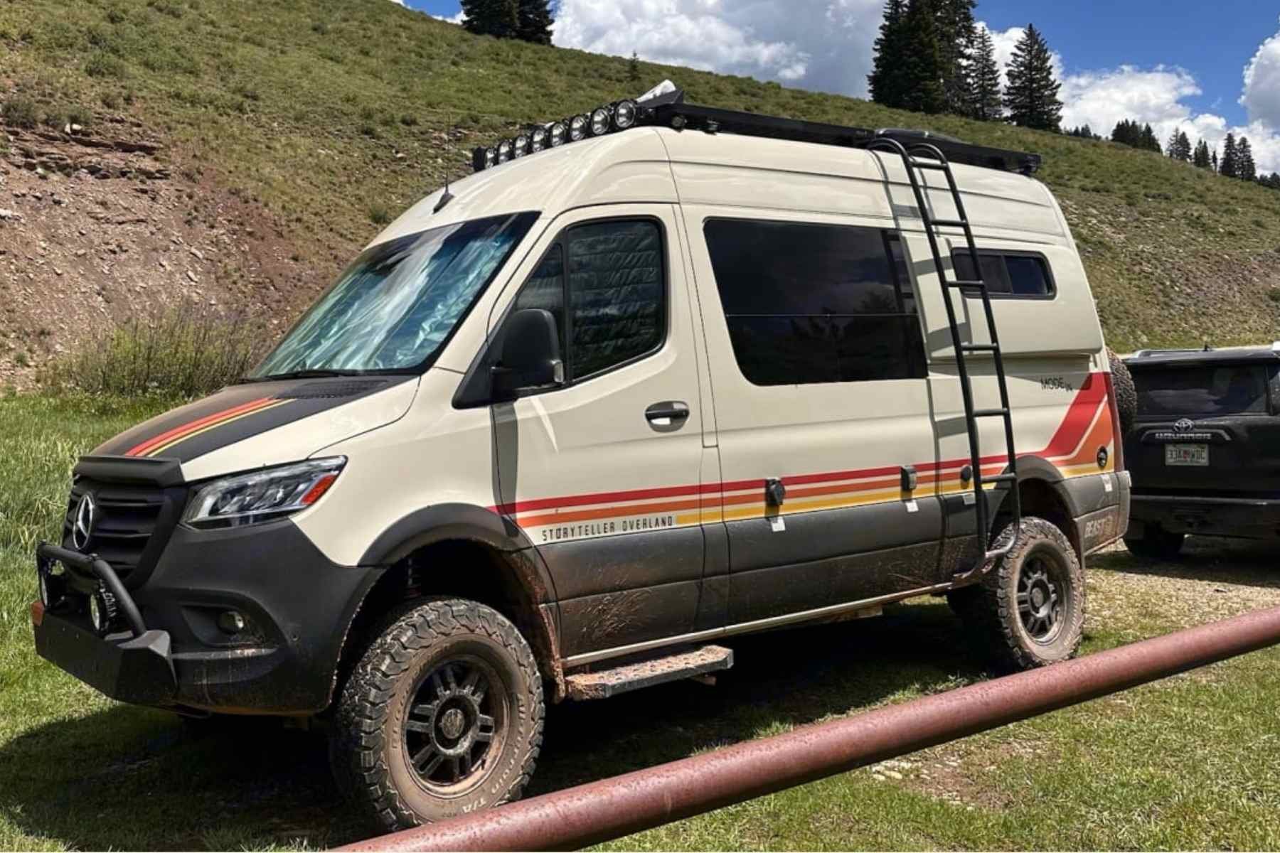 Beige Mercedes Sprinter 4x4 camper van with off-road tires and roof rack parked in the mountains, representing a premium Tennessee camper van rental for Smoky Mountains and backcountry road trips.