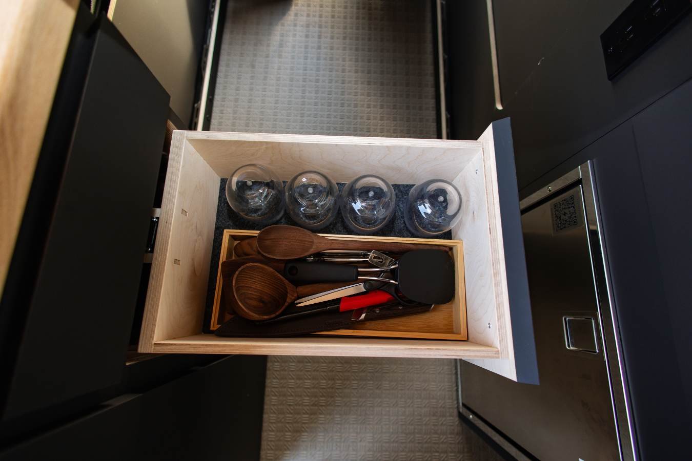 Utensil drawer with cups and cooking tools in conversion van.
