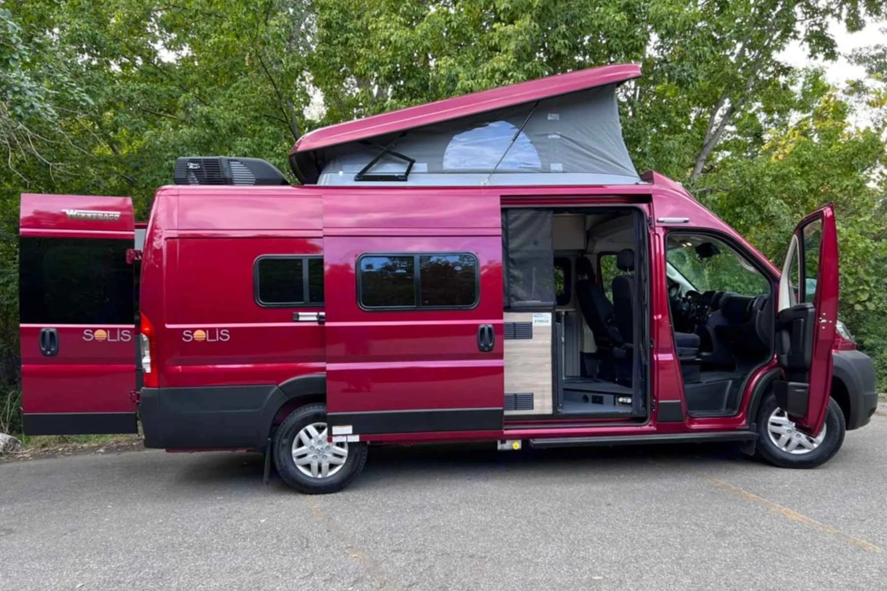 Red Winnebago Solis pop-top campervan rental in Salt Lake City featuring dual queen beds and airport delivery for turnkey Utah road trip adventures.