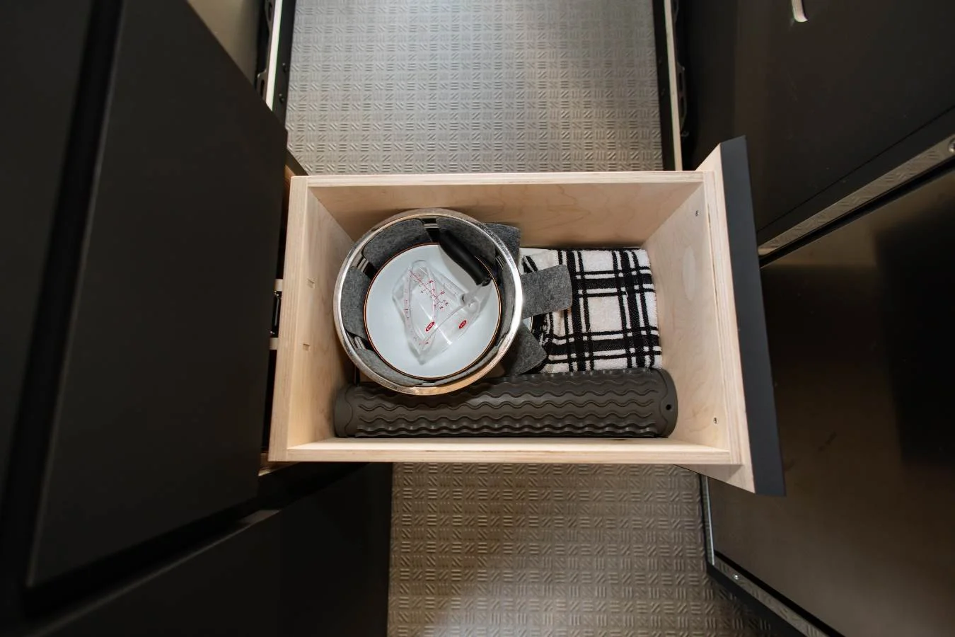 Kitchen drawer with cookware and utensils in premium camper van interior.