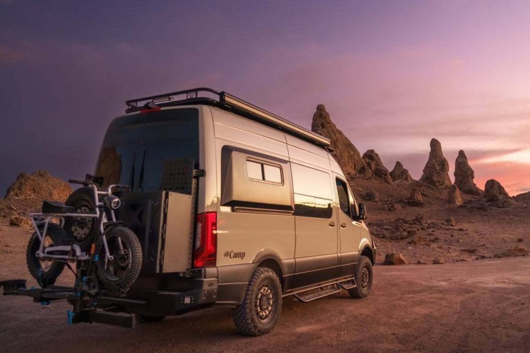 Mercedes-Benz Sprinter camper van rental in desert at sunset with bike rack and rooftop rack — altCamp