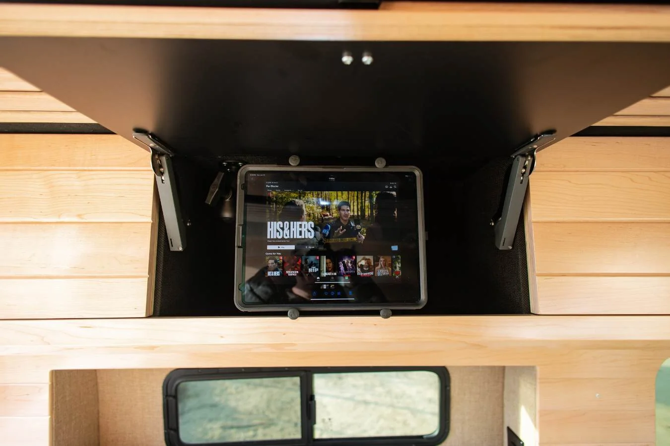 Mounted tablet entertainment system above bed in luxury camper van.