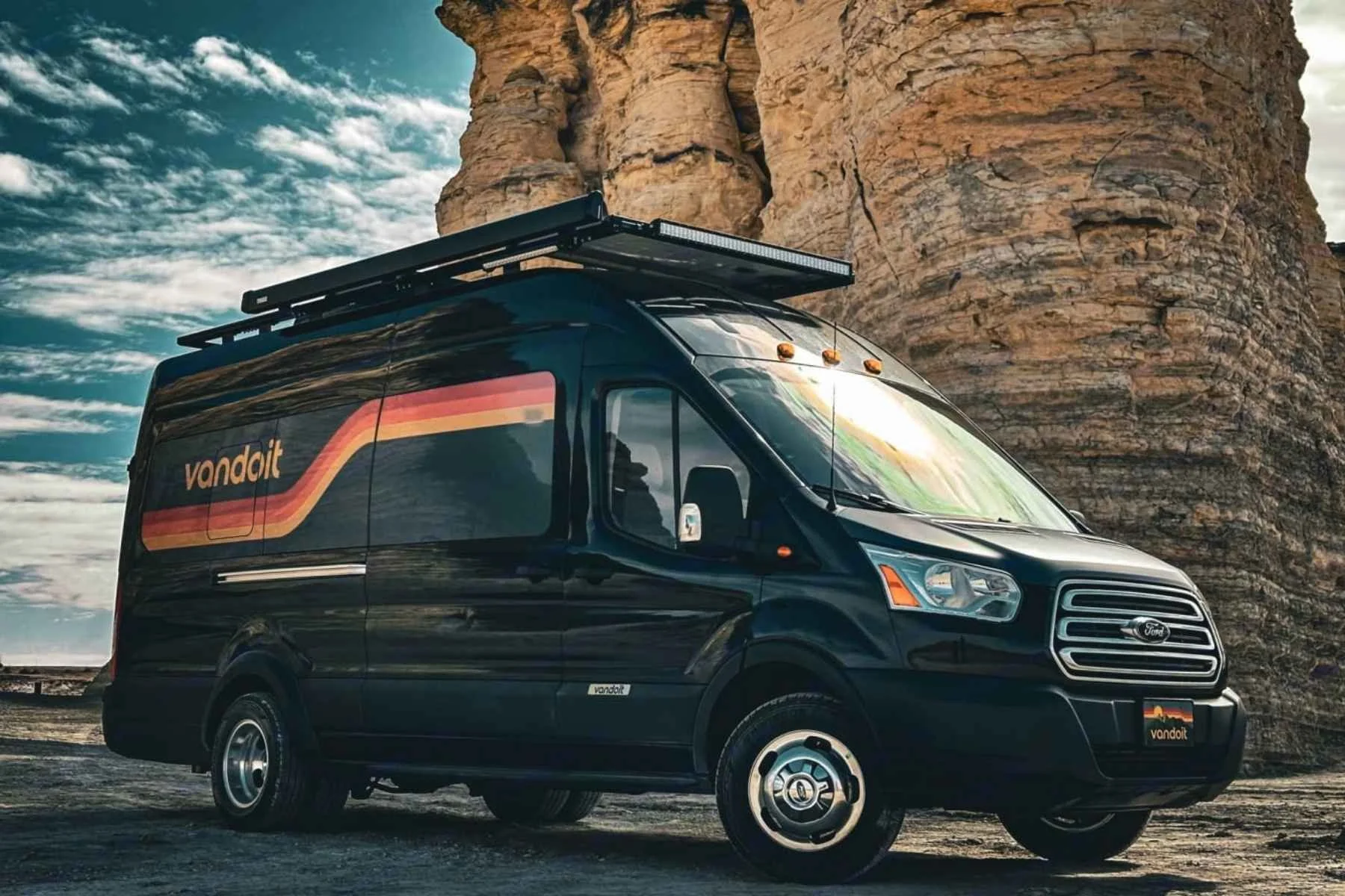 Modern black camper van parked near a rocky canyon landscape, featuring an adventure-ready design ideal for road trips and outdoor travel.