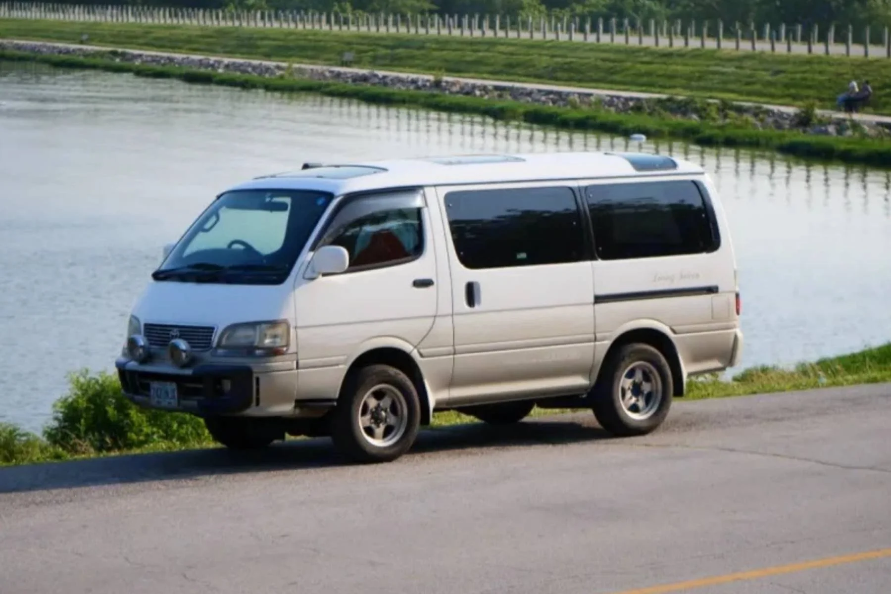 Budget camper van rental in Kansas, showing a silver camper van parked beside a river on a paved road.