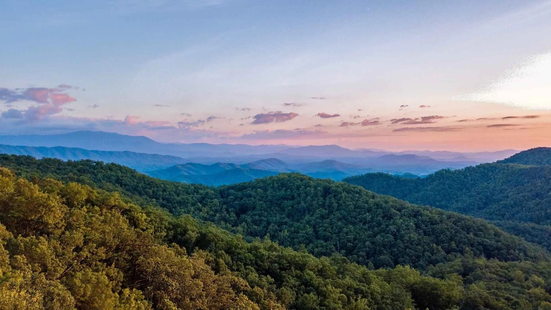 Tennessee mountain landscape at sunset with rolling forested hills and pastel skies, featured on a conversion van rental FAQ page for road trips and camping in Tennessee.