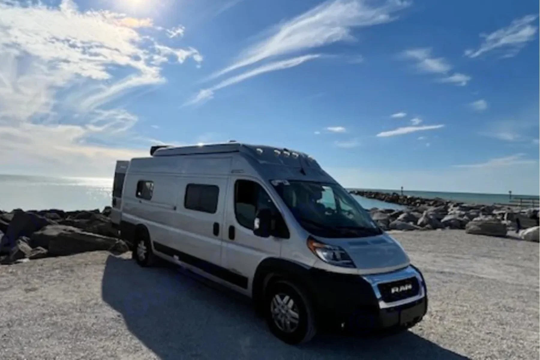 Pop-up camper van rental parked by the ocean with pop-top roof extended