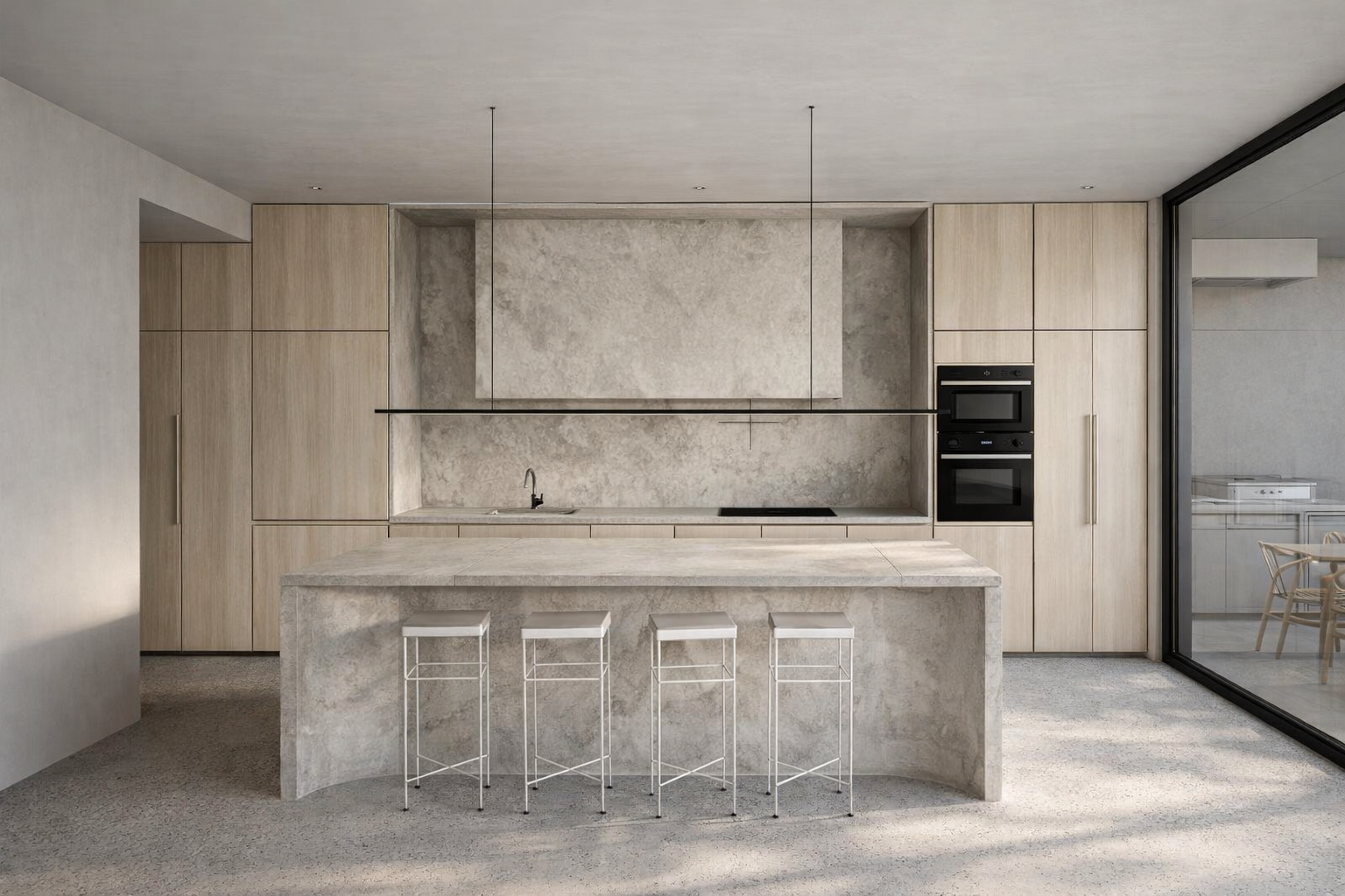 Modern minimalist kitchen with light wood cabinets, concrete island, and built-in black appliances, with a large sliding glass door to the right.