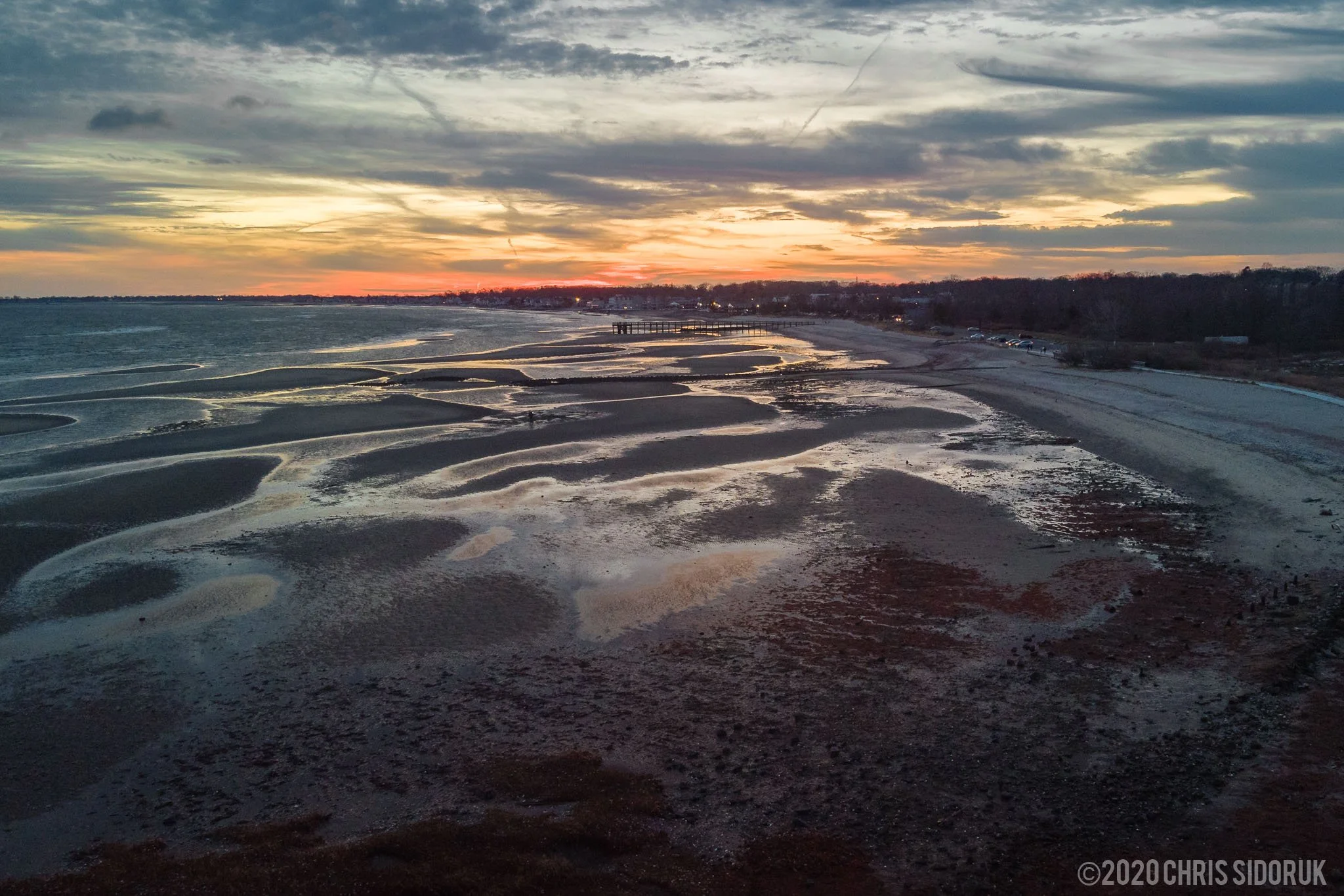 Aerial view of Walnut Beach shoreline at sunset with tidal patterns and reflections in Milford, Connecticut