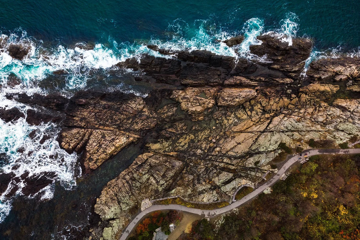 An aerial view of Marginal Way in Ogunquit, Maine shows waves breaking against the rugged Atlantic coastline.