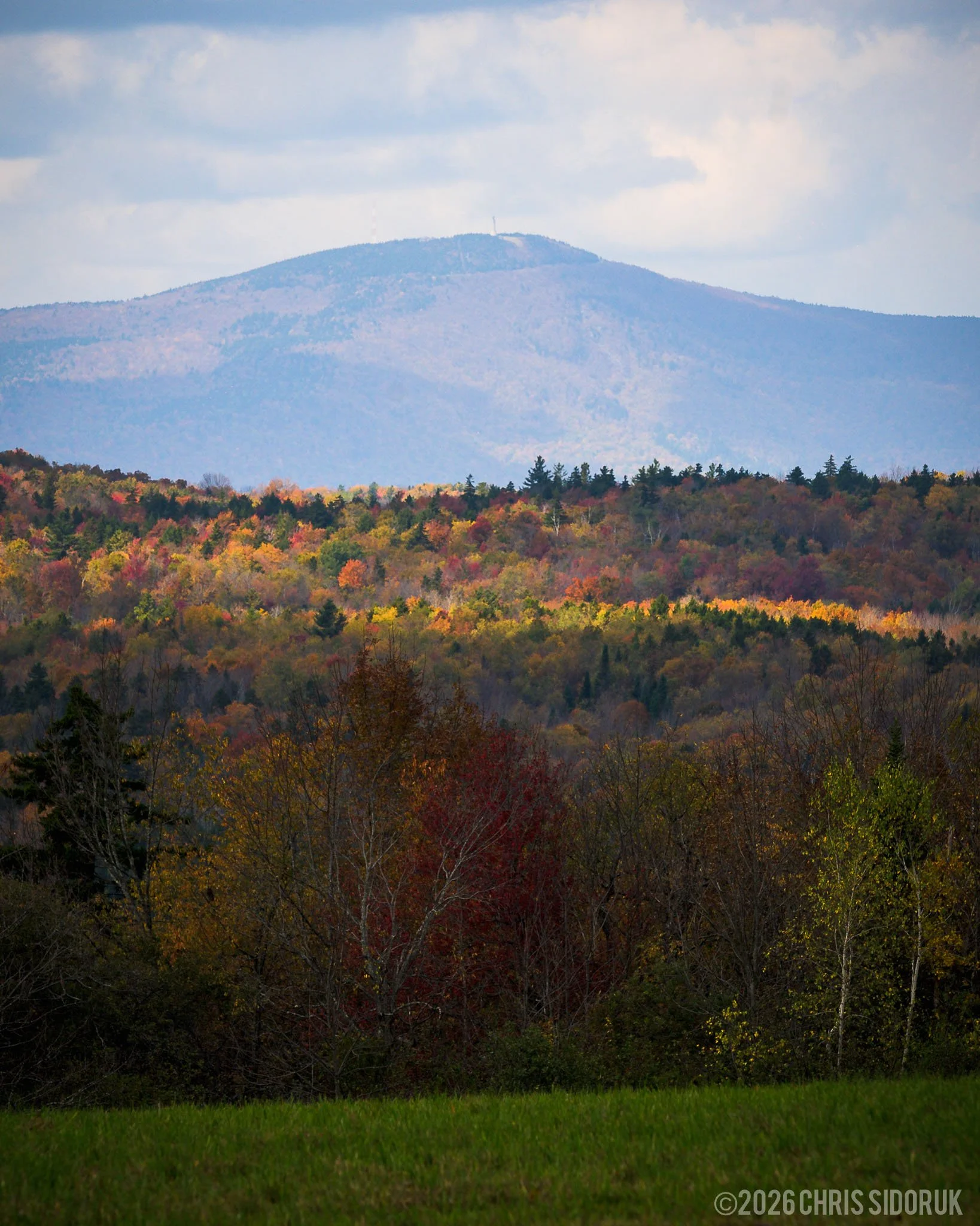 Mount Greylock rising in the distance above colorful fall foliage layers in the Berkshire Mountains of Massachusetts.