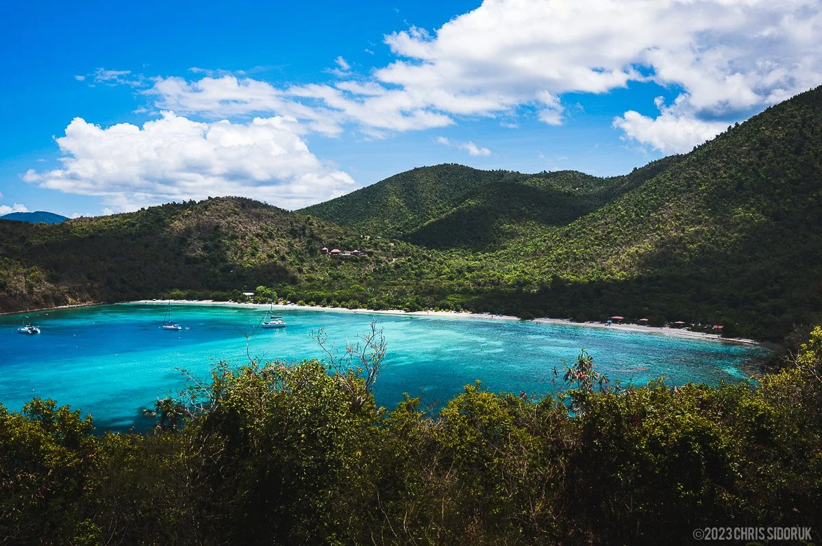 Maho Bay in St John USVI with calm turquoise water, anchored sailboats, and green hills surrounding the beach