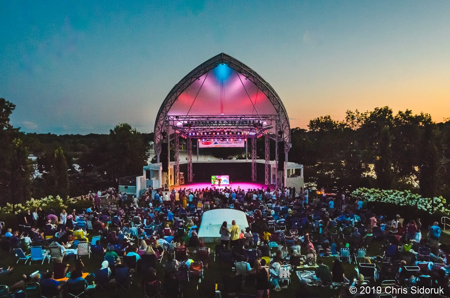 crowd gathered on the lawn at Levitt Pavilion during a live outdoor concert at sunset