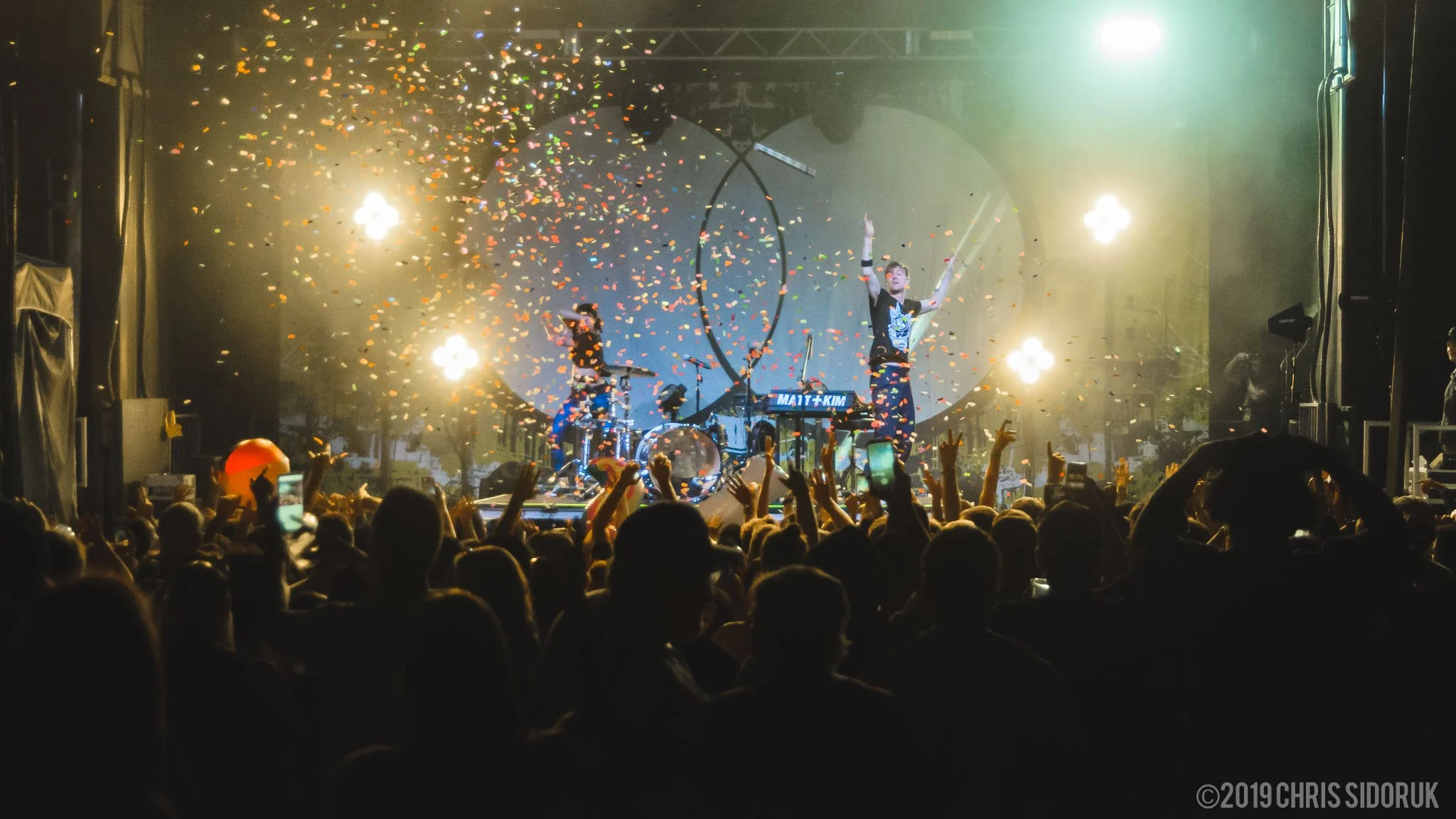 Matt + Kim Live performance at Road Jam Music Festival in Stratford, Connecticut, on June 22, 2019, with stage and outdoor crowd visible.