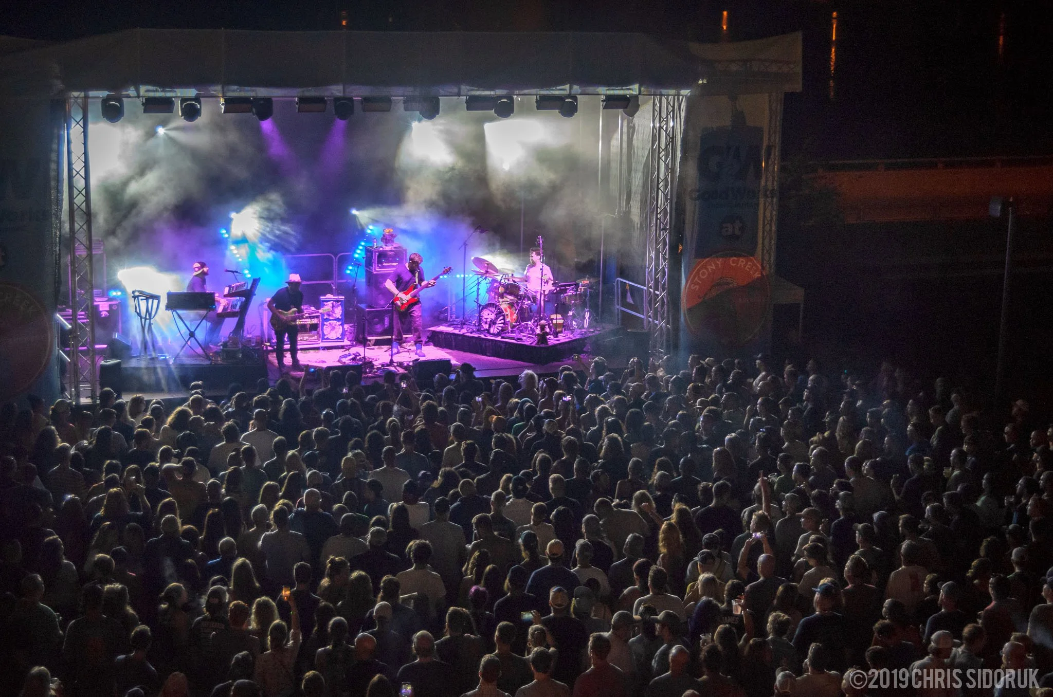 Twiddle performing live at Stony Creek in Branford, Connecticut, on August 30, 2019, with outdoor stage and crowd visible.