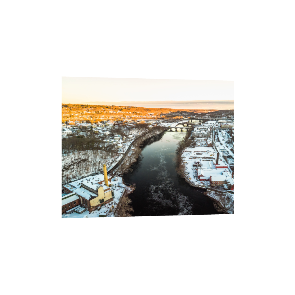 Fine art print of an aerial winter river scene with a snow-covered town and bridges at sunset