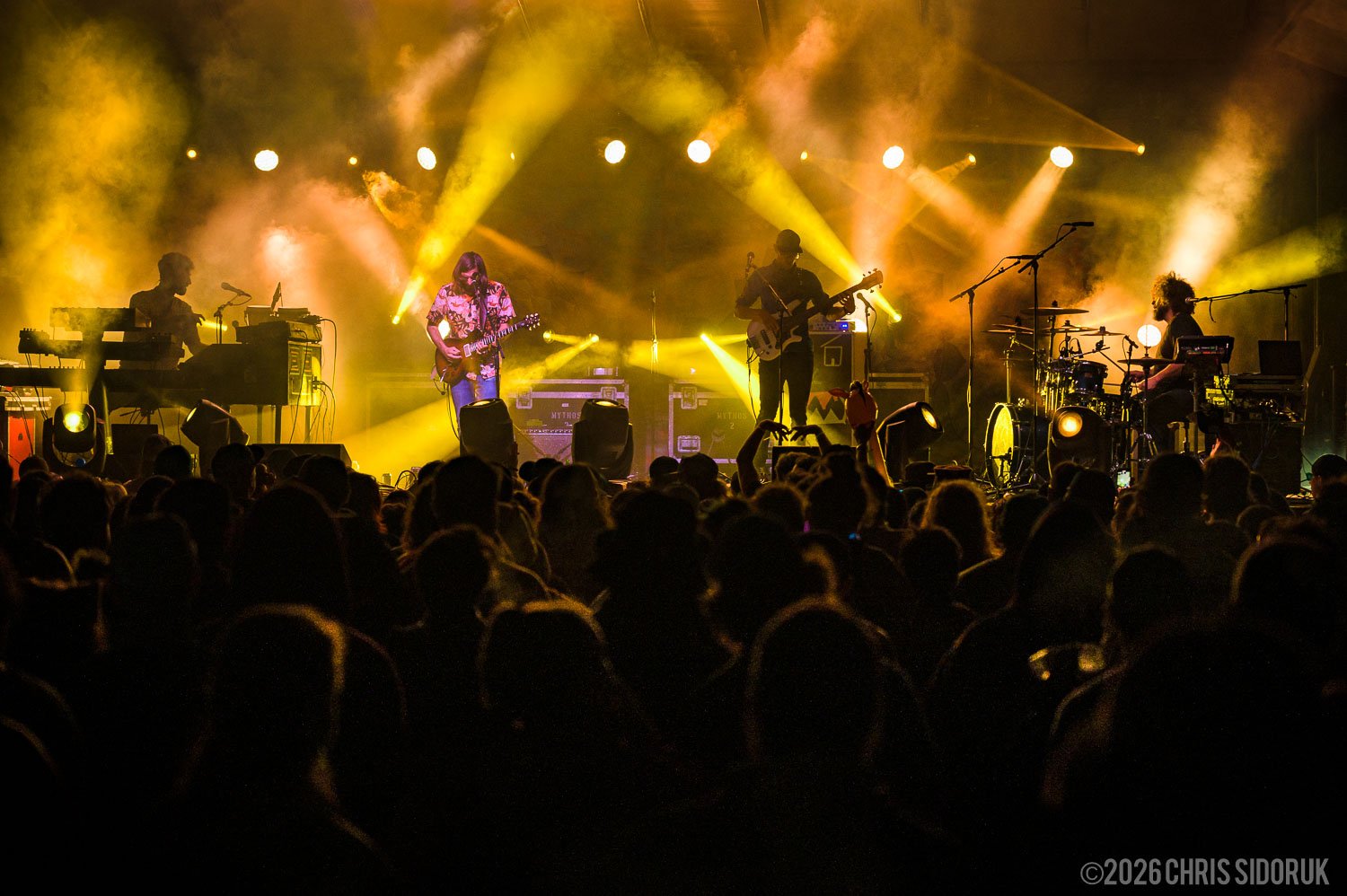 Dopad performing on stage with vibrant stage lighting and a crowd in the foreground