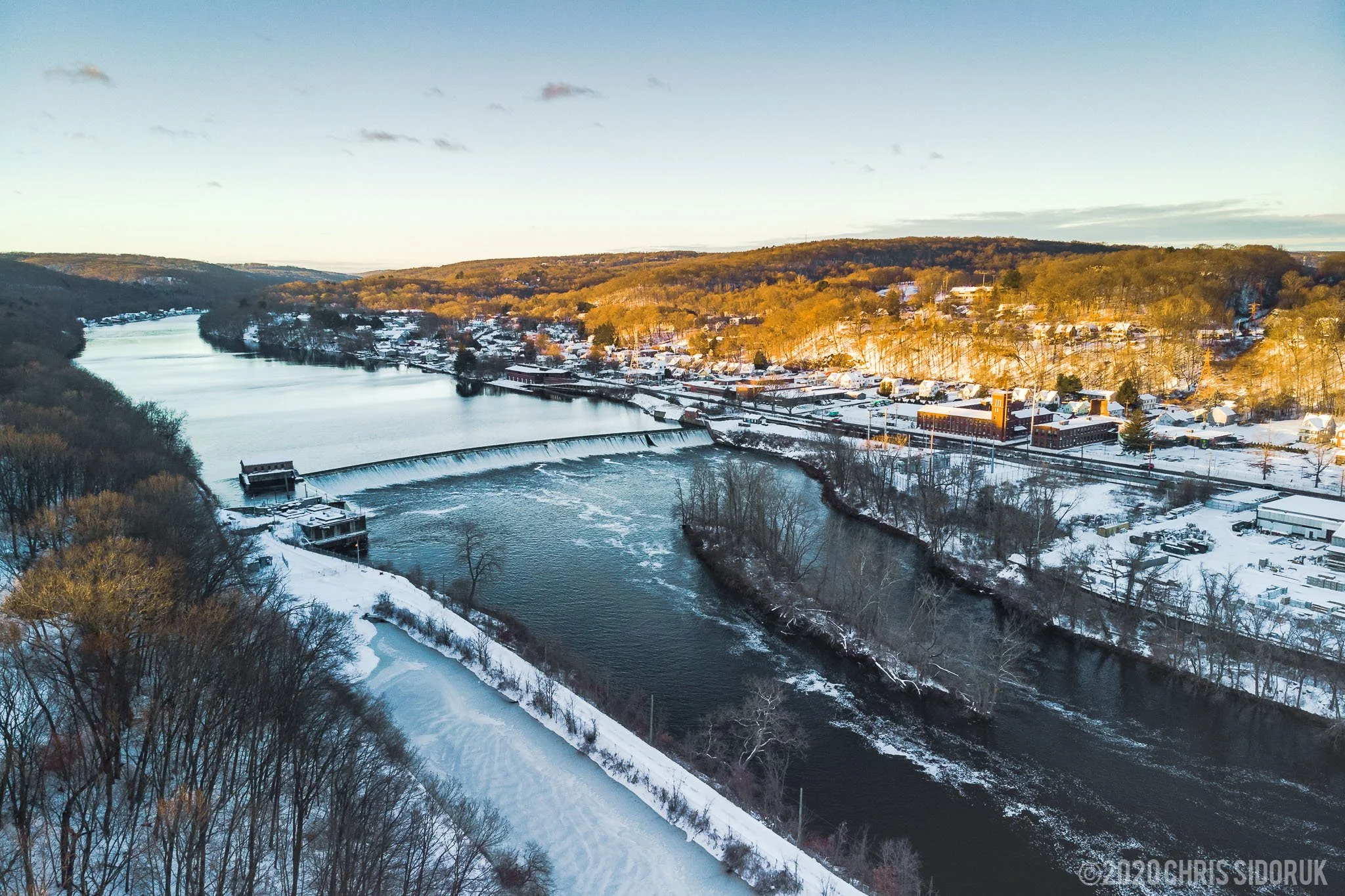 Aerial view from Shelton, Connecticut, of the Housatonic River and Ousatonic Dam in winter, with snow-covered riverbanks.
