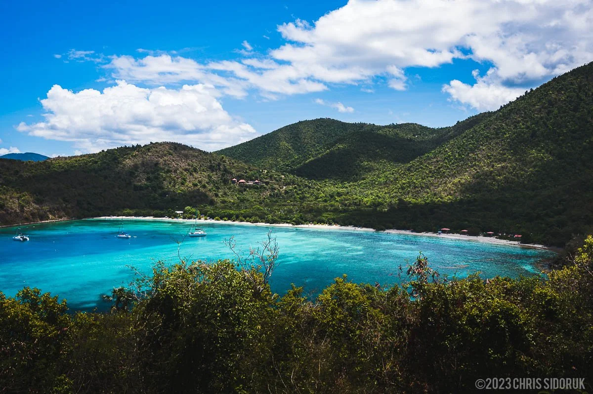 Maho Bay in St John USVI with calm turquoise water, anchored sailboats, and green hills surrounding the beach