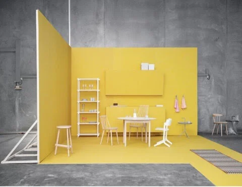 Minimalist room with yellow walls, table, chairs, and shelves.