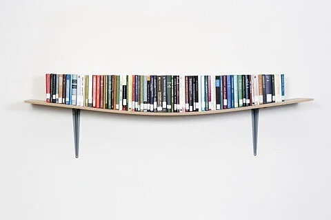 Curved wall-mounted bookshelf with various books