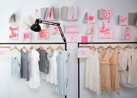 Clothing store display with dresses on hangers and wall art
