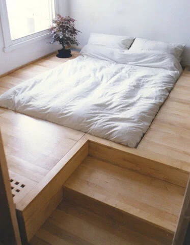 Minimalist bedroom with a platform bed and a small potted plant.
