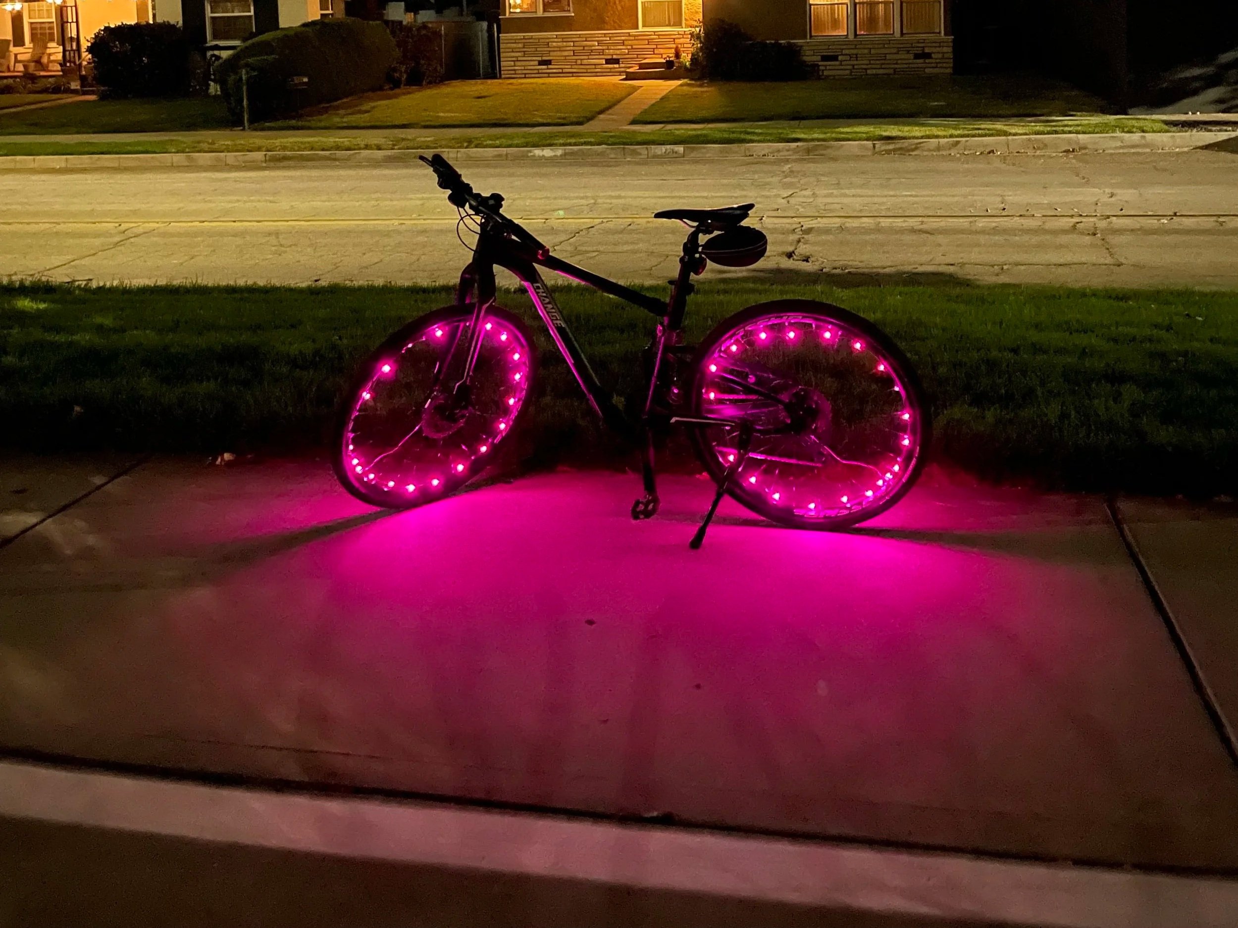 night time bike on kick stand with lights on wheels, lights are fuscia
