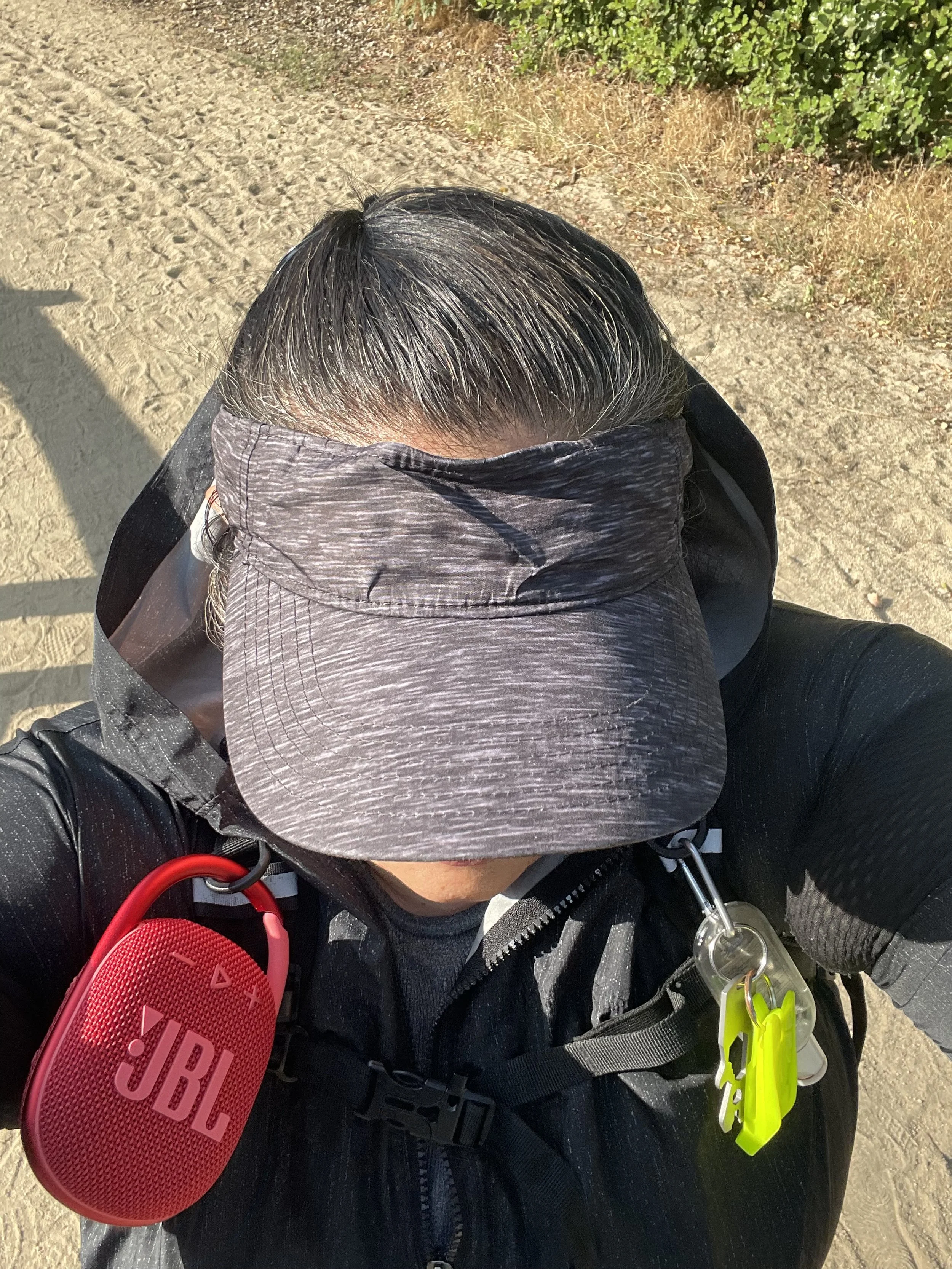 Coach Vida grey visor selfie, red JBL speaker clipped on shoulder