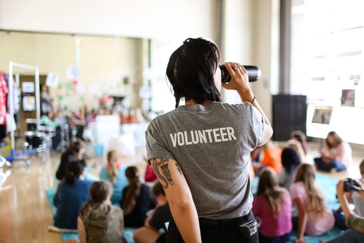 Person with t-shirt that says Volunteer on the back overlooking a workshop