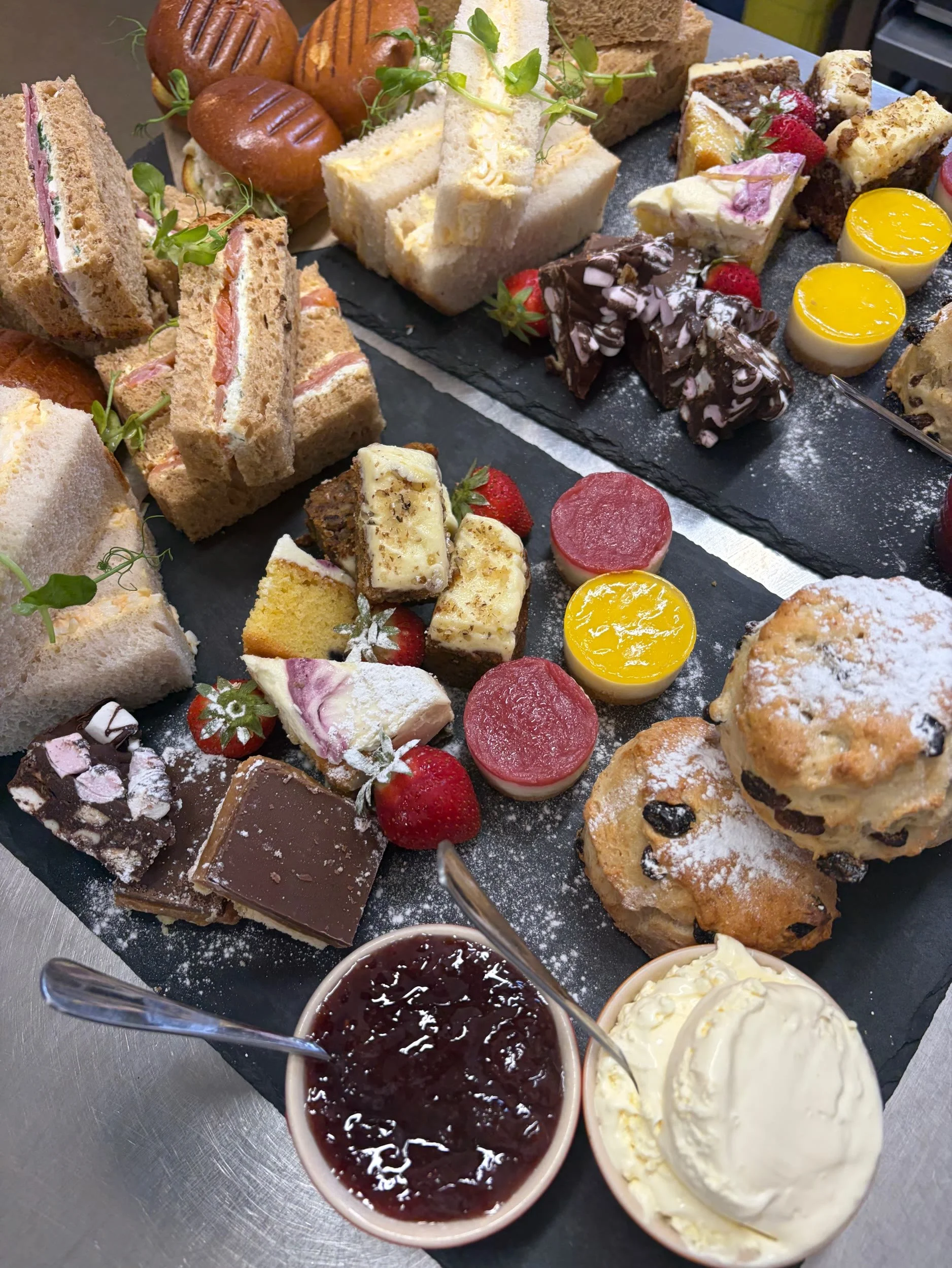 Afternoon tea board with sandwiches, scones and cakes