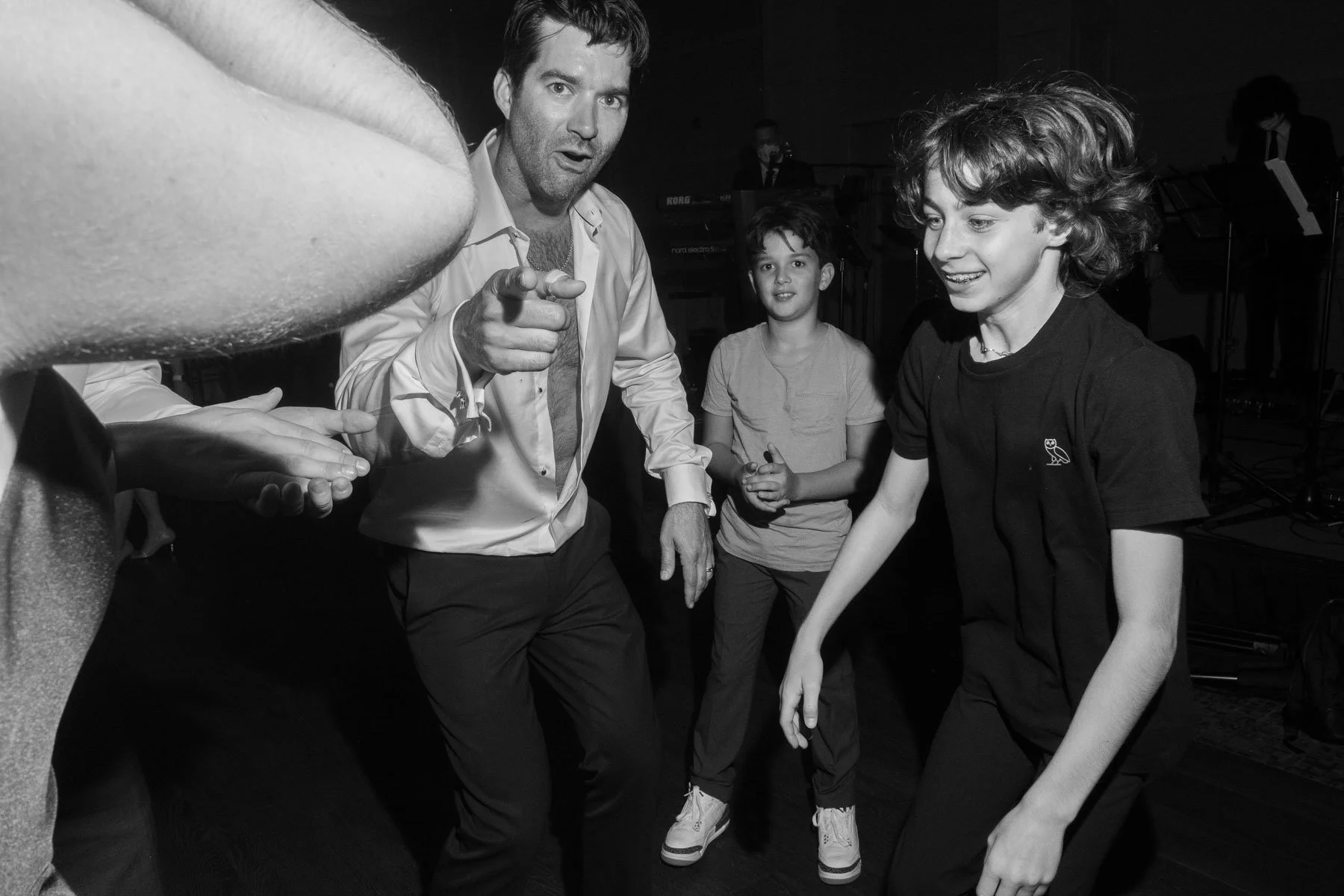Black and white photo of people dancing and interacting at a party.