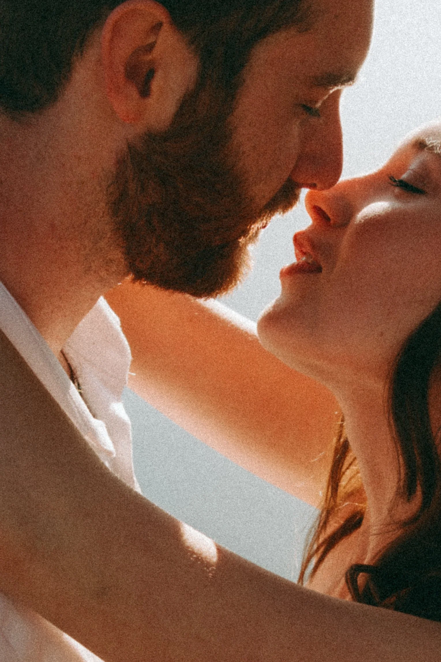 A close-up of a couple about to kiss, with their faces close together and eyes closed.