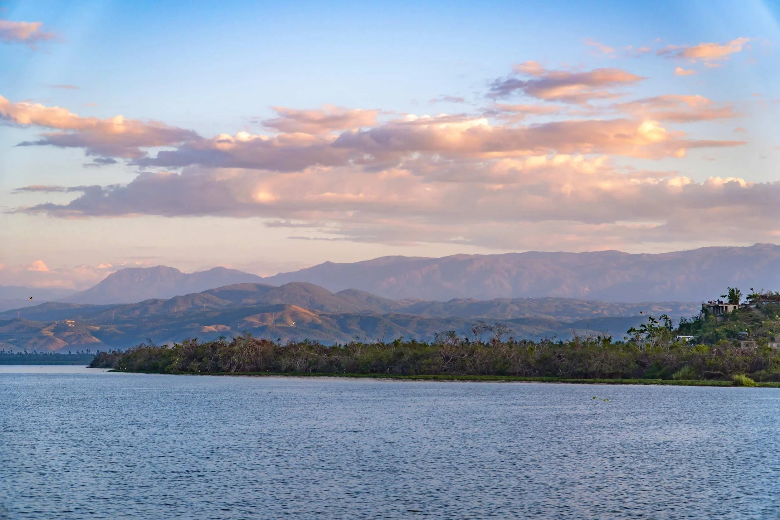Paisaje con un laguna de Coyuca en primer plano, montañas en el fondo y un cielo con nubes color rosa y azul. playa pie de la cuesta, Hotel boutique  baXar Acapulco