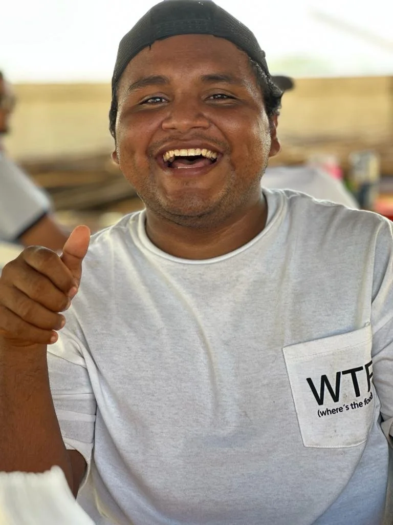 Hombre local Acapulqueño con camiseta blanca y gorra negra sonriendo y haciendo un gesto de pulgar arriba en un ambiente informal. Hotel boutique playa pie de la cuesta, baXar Acapulco