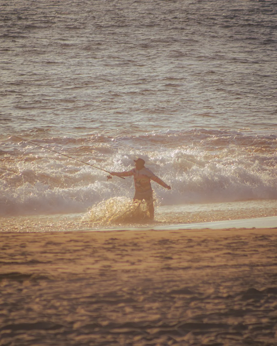 Persona pescando en la orilla del mar en la playa al atardecer.  Hotel boutique baXar playa Pie de la cuesta Acapulco