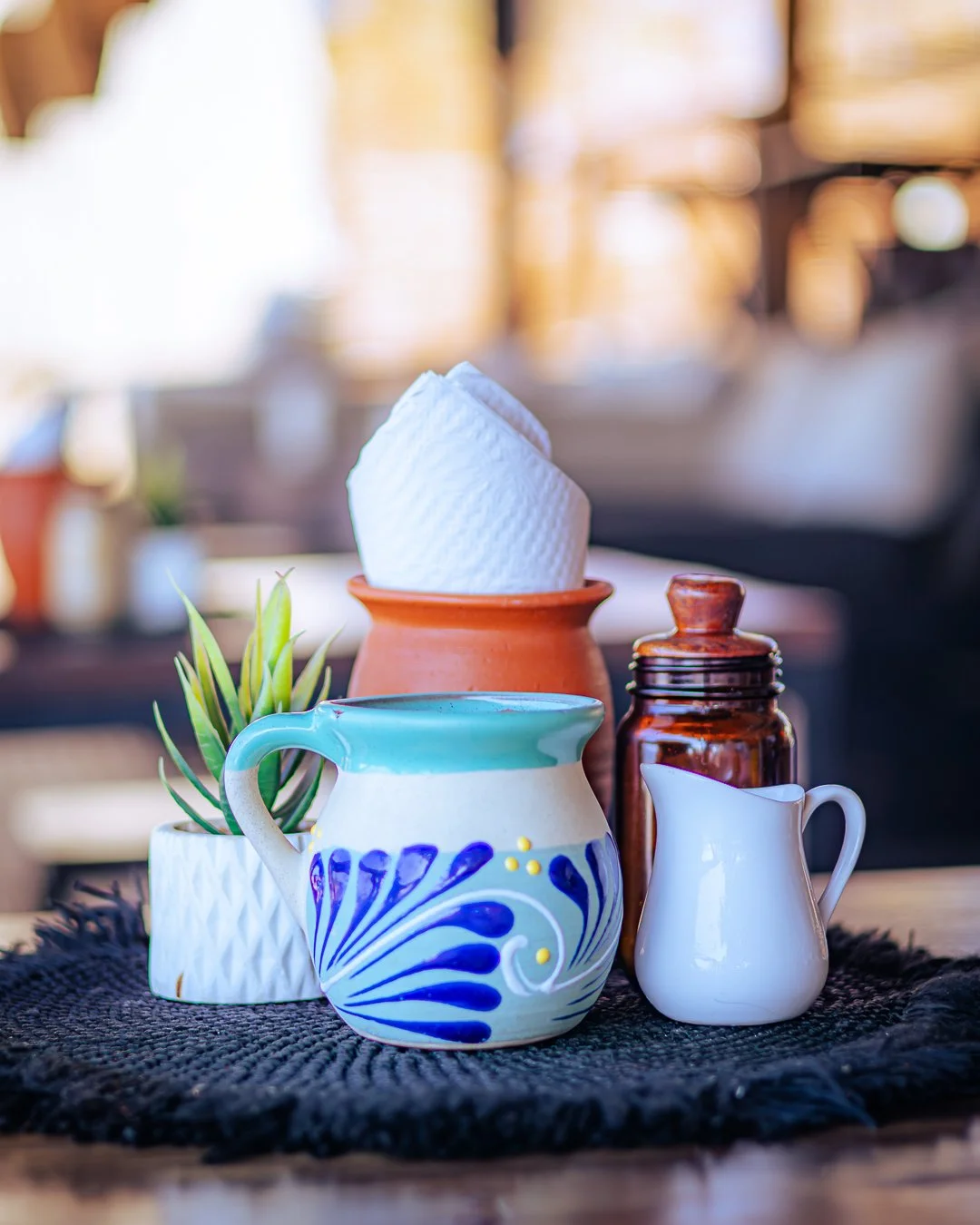 Conjunto de tazas y jarrones decorativos en una mesa, con una planta pequeña.  Hotel boutique baXar playa Pie de la cuesta Acapulco