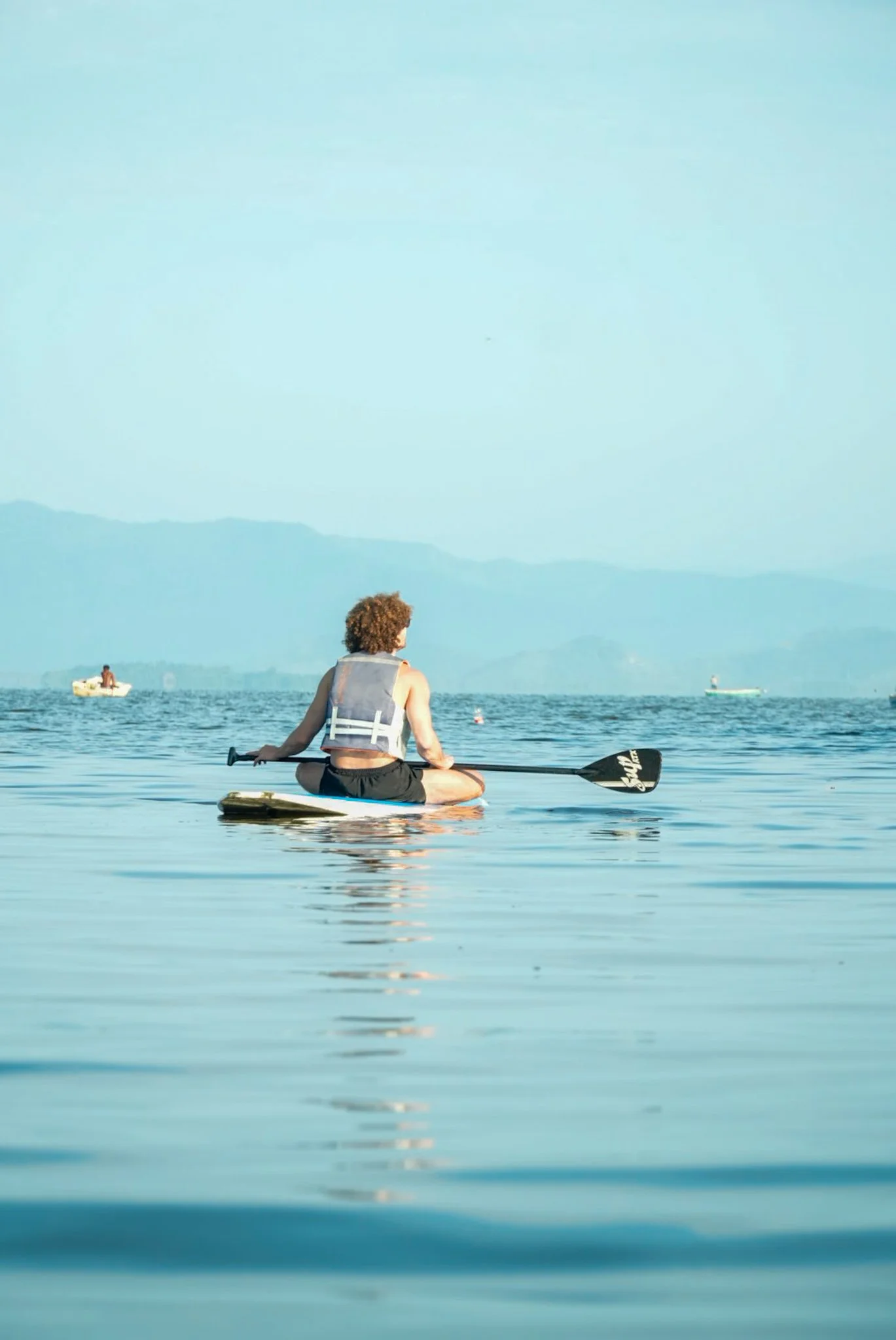Persona en kayak en laguna de coyuca con montañas de fondo en un día despejado. baxar hotel wellness y club de playa