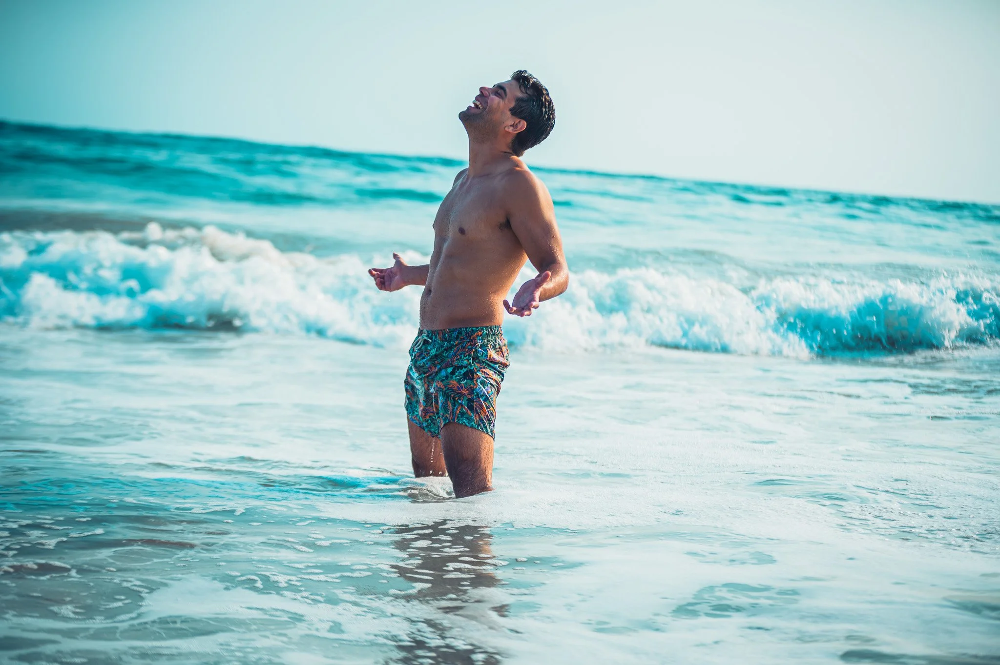 Un hombre feliz en la playa, luciendo sombrero y bañador, disfrutando del mar y el sol. Hotel baXar pie de la cuesta