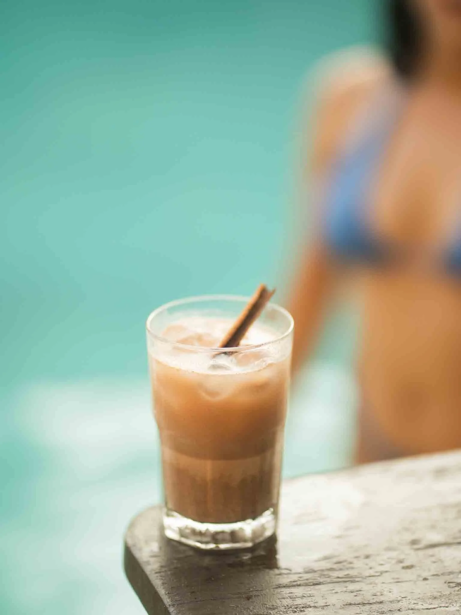 Un vaso con una bebida cremosa y una canela en rama en la parte superior, colocado sobre una superficie de madera. hotel baxar pie de la cuesta 