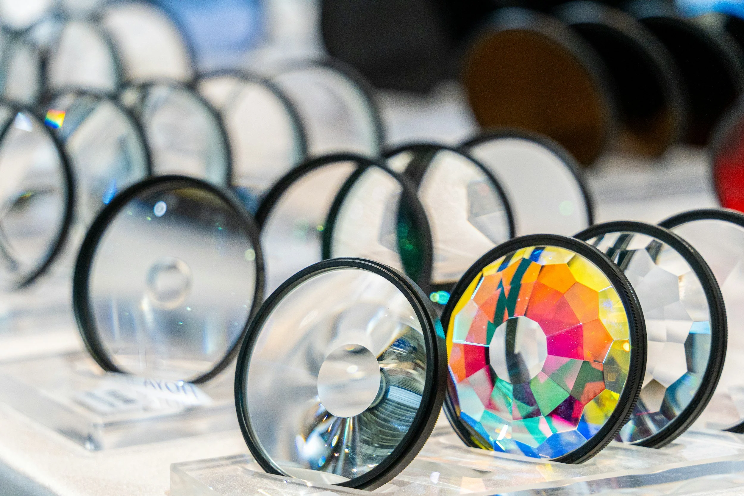 Six camera lens filters with colored glass lenses placed on a wooden surface.
