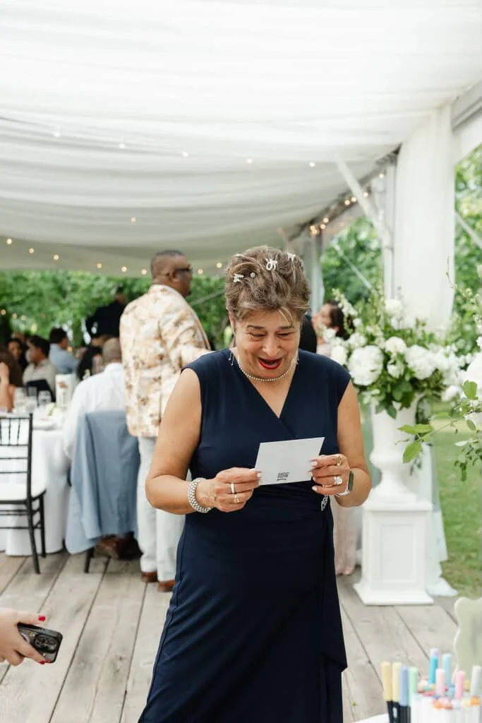 A woman in a dark blue dress look at a portrait of herself at a celebration or wedding reception outdoors.