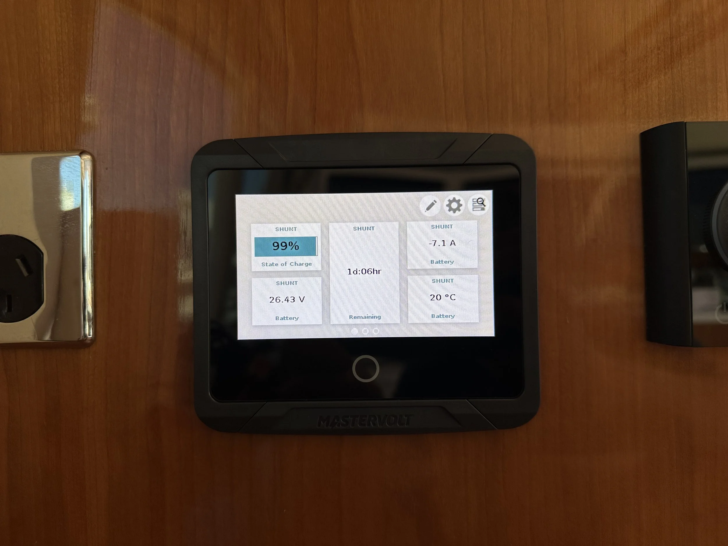 A Mastervolt battery monitor displaying 99% charge, voltage of 26.43V, current of -7.1A, temperature of 20°C, and an estimated remaining time of 1 day and 6 hours.