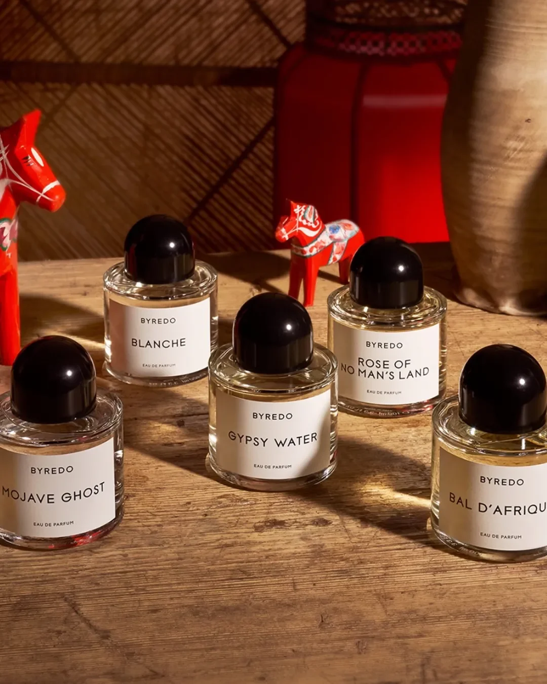 Byredo perfume bottles arranged together on a rustic wooden table.