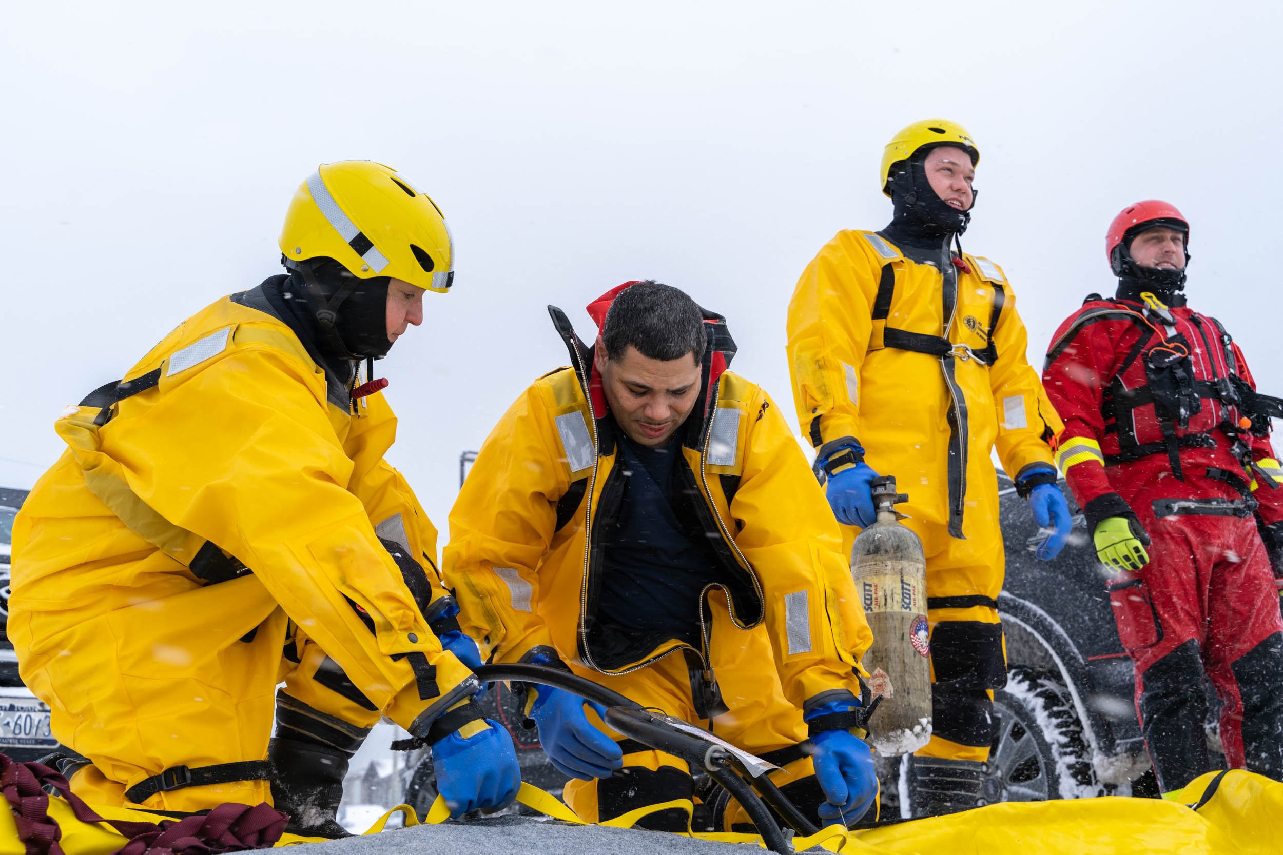 Laura Johnson, Victor Pacheco, unknown, and Tyler Makaravitz blow up an inflatable raft for ice rescues in Irondequoit Bay, NY on February 18, 2022. New York firefighters train for ice rescues once a year and spend an hour out in the freezing temper