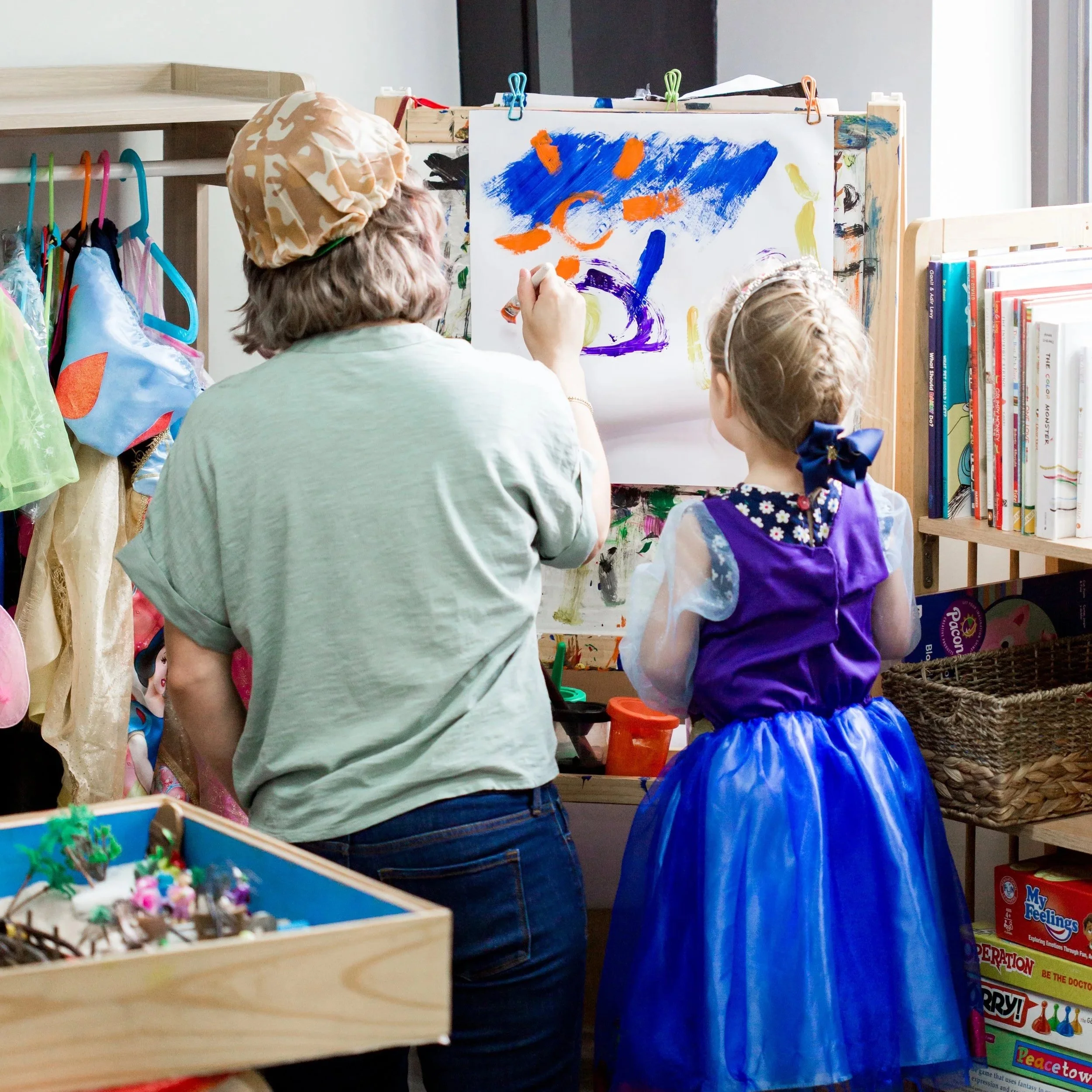 Young child showcasing an art easel in a bright therapy office.