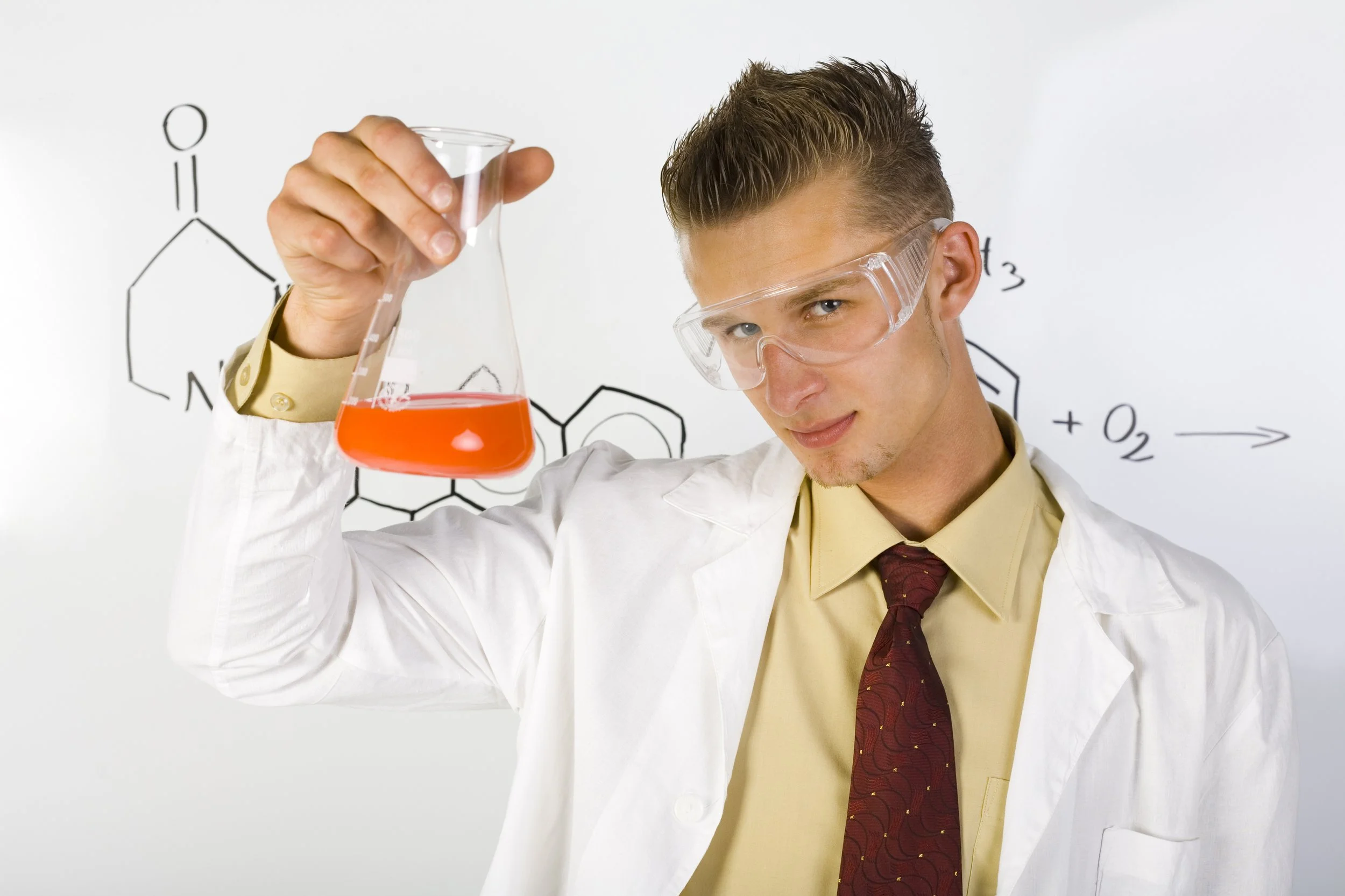 Male chemist holding beaker of orange liquid